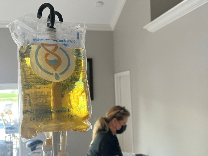 A photo of an IV bag and a nurse in the background